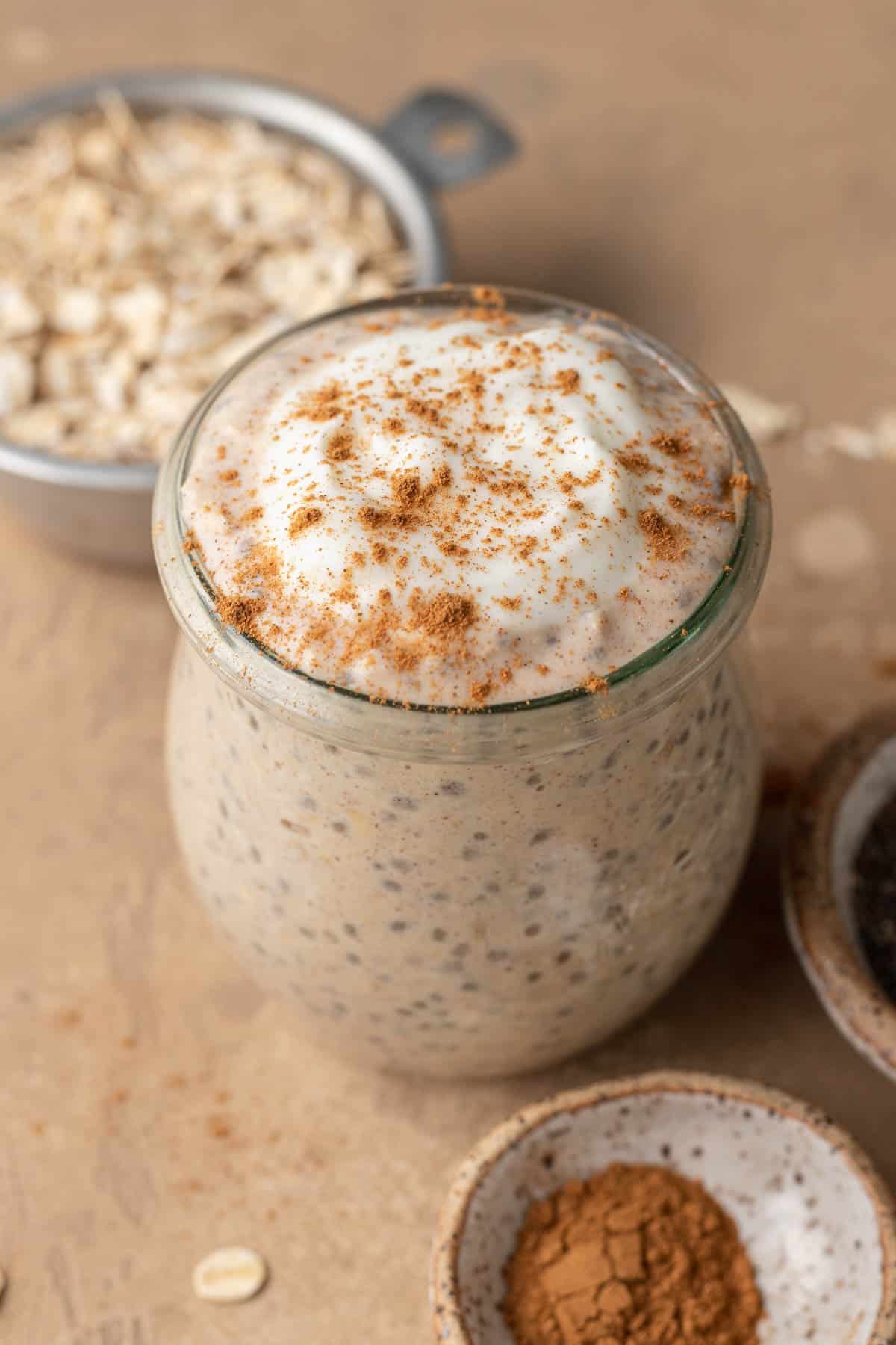 cinnamon roll overnight oats with icing on top, topped with a sprinkle of cinnamon.