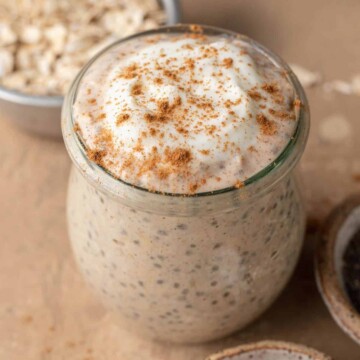 cinnamon roll overnight oats in a glass jar with cinnamon sprinkled on top.