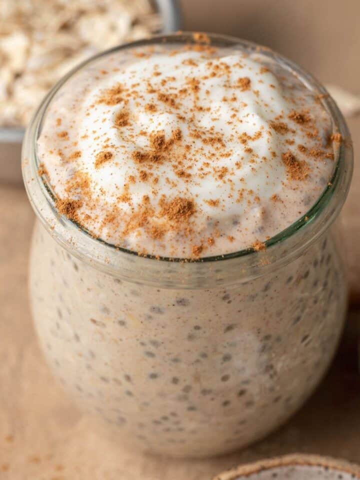 cinnamon roll overnight oats in a glass jar with cinnamon sprinkled on top.