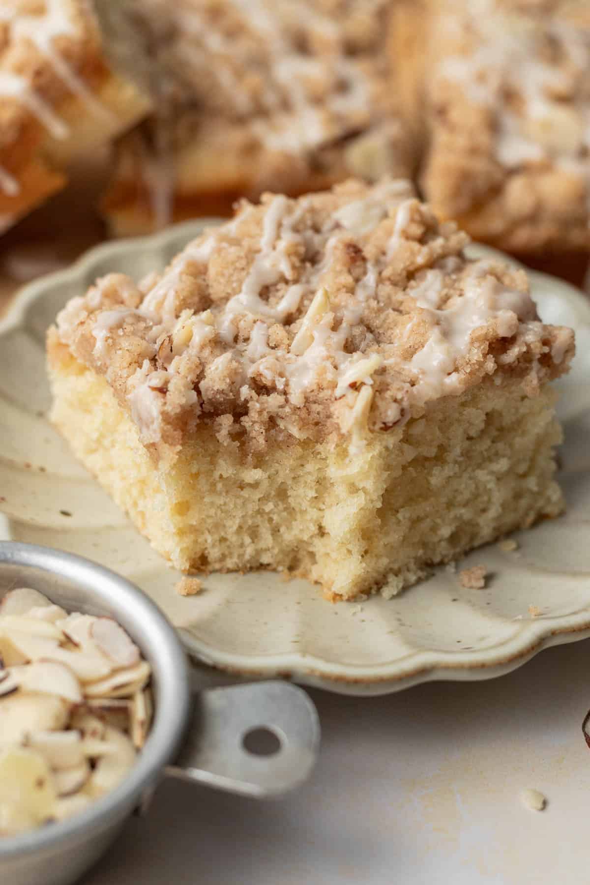 piece of coffee cake on a white plate with a bite taken out of the front of it.