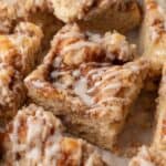 square slice of coffee cake with icing drizzled on top surrounded by other slices.