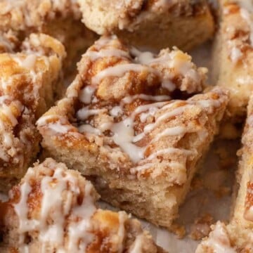 square slice of coffee cake with icing drizzled on top surrounded by other slices.