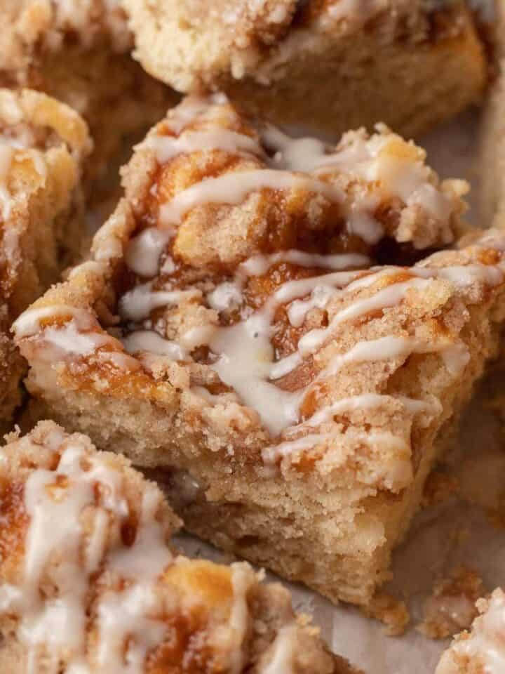 square slice of coffee cake with icing drizzled on top surrounded by other slices.