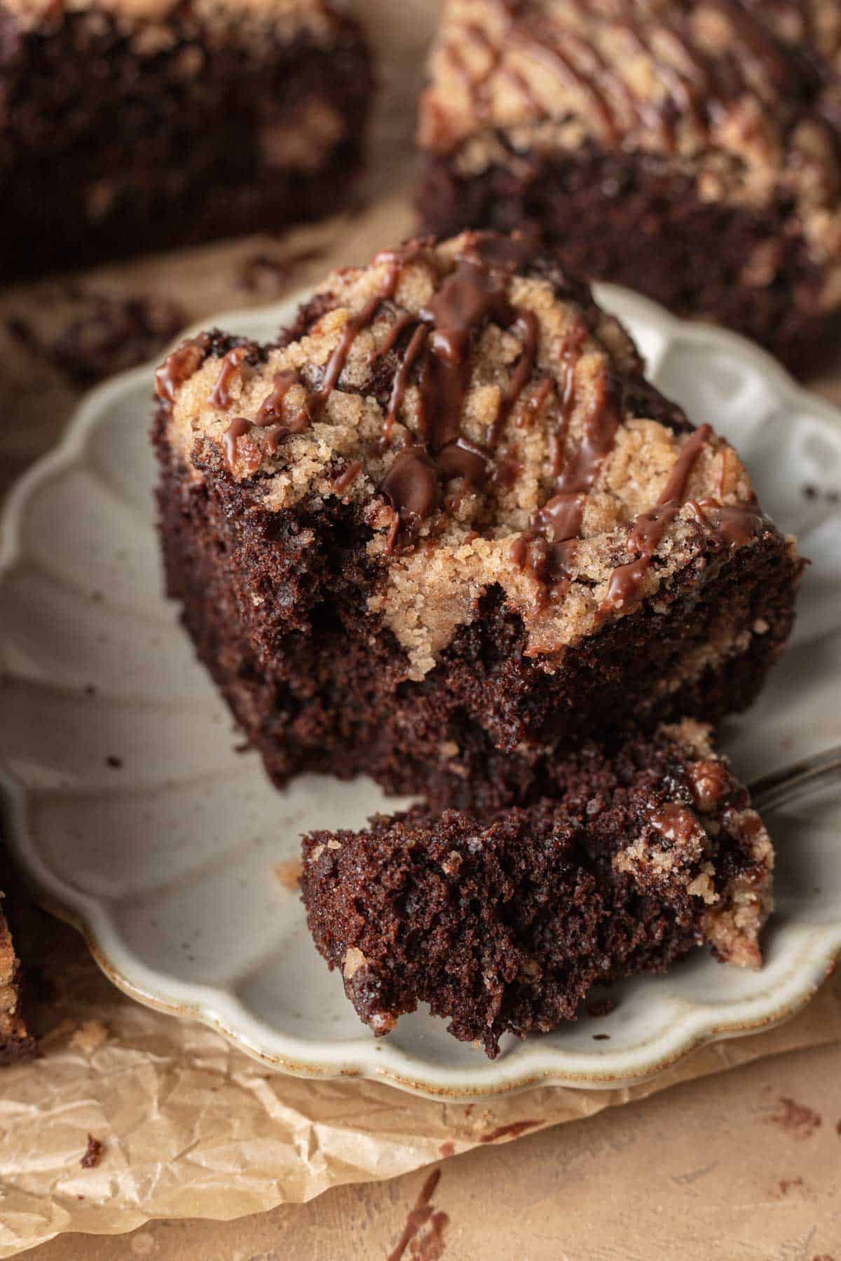 fork taking bite out of chocolate coffee cake on a white plate.