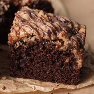 slice of chocolate coffee cake with streusel on top drizzled with chocolate icing.