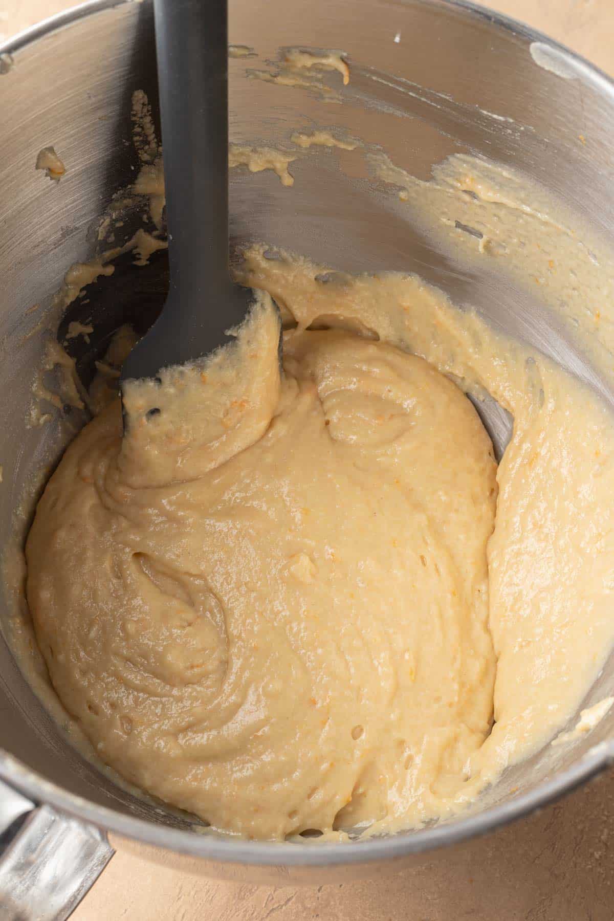 orange cake batter mixed together in mixing bowl.