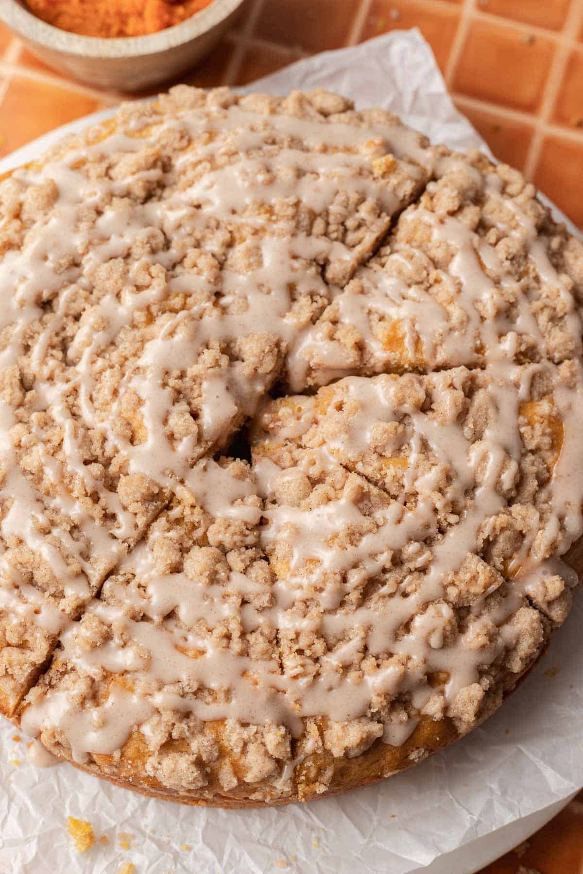 pumpkin coffee cake with pumpkin glaze drizzled on top with 4 slices cut into cake.