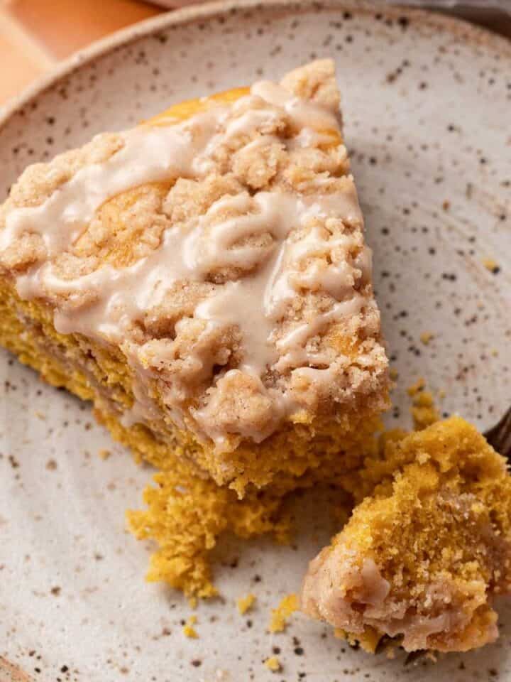 slice of pumpkin coffee cake on a plate with a fork taking a bite from it.