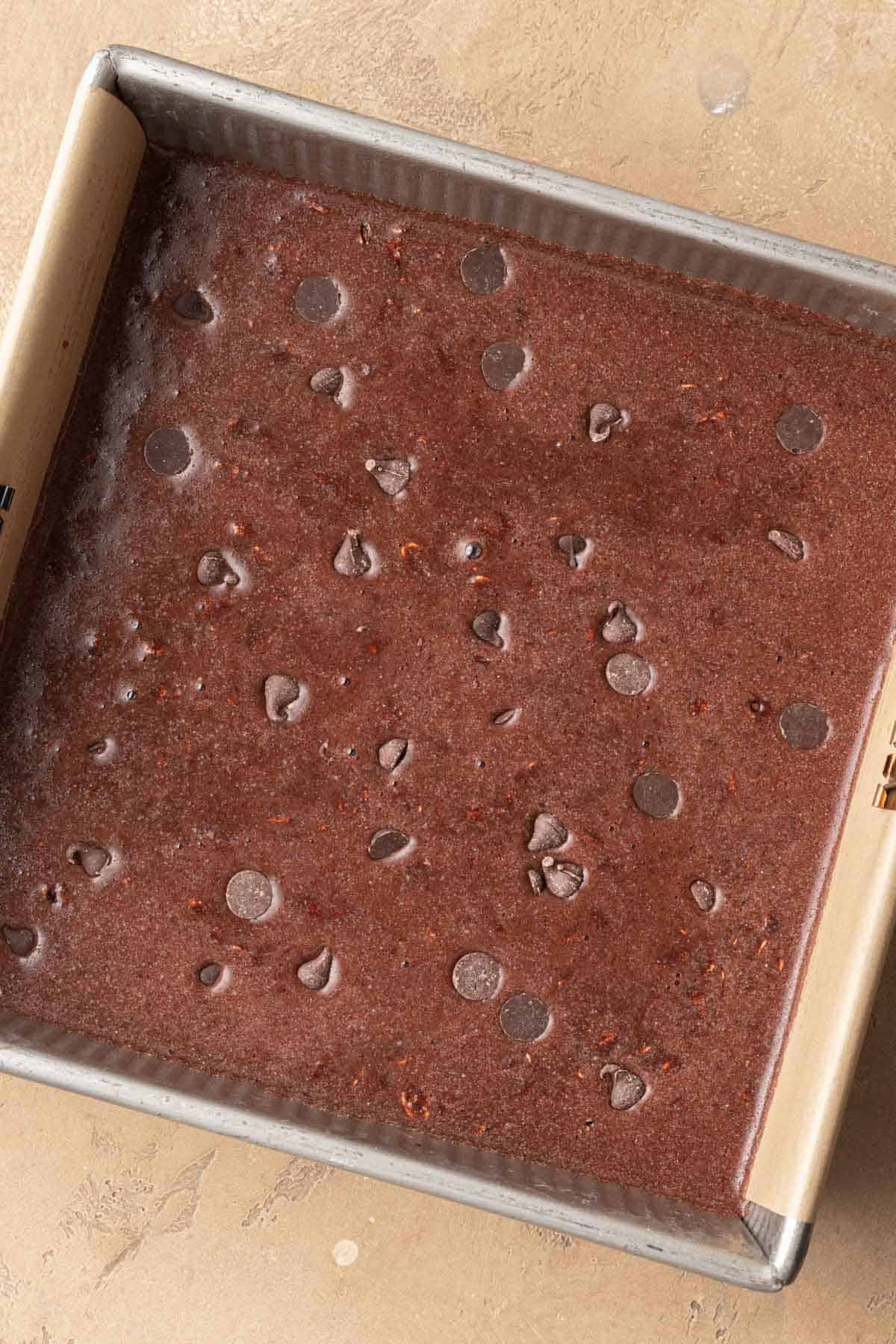 brownie baked oatmeal batter in the pan topped with extra chocolate chips before getting baked.