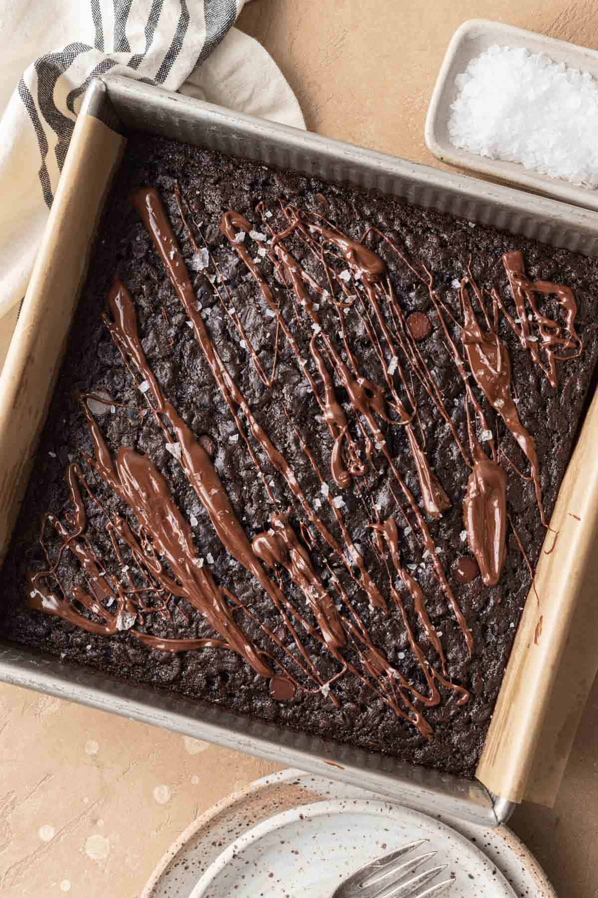 overhead shot of brownie baked oatmeal after being baked, topped with melted chocolate and flakey sea salt.