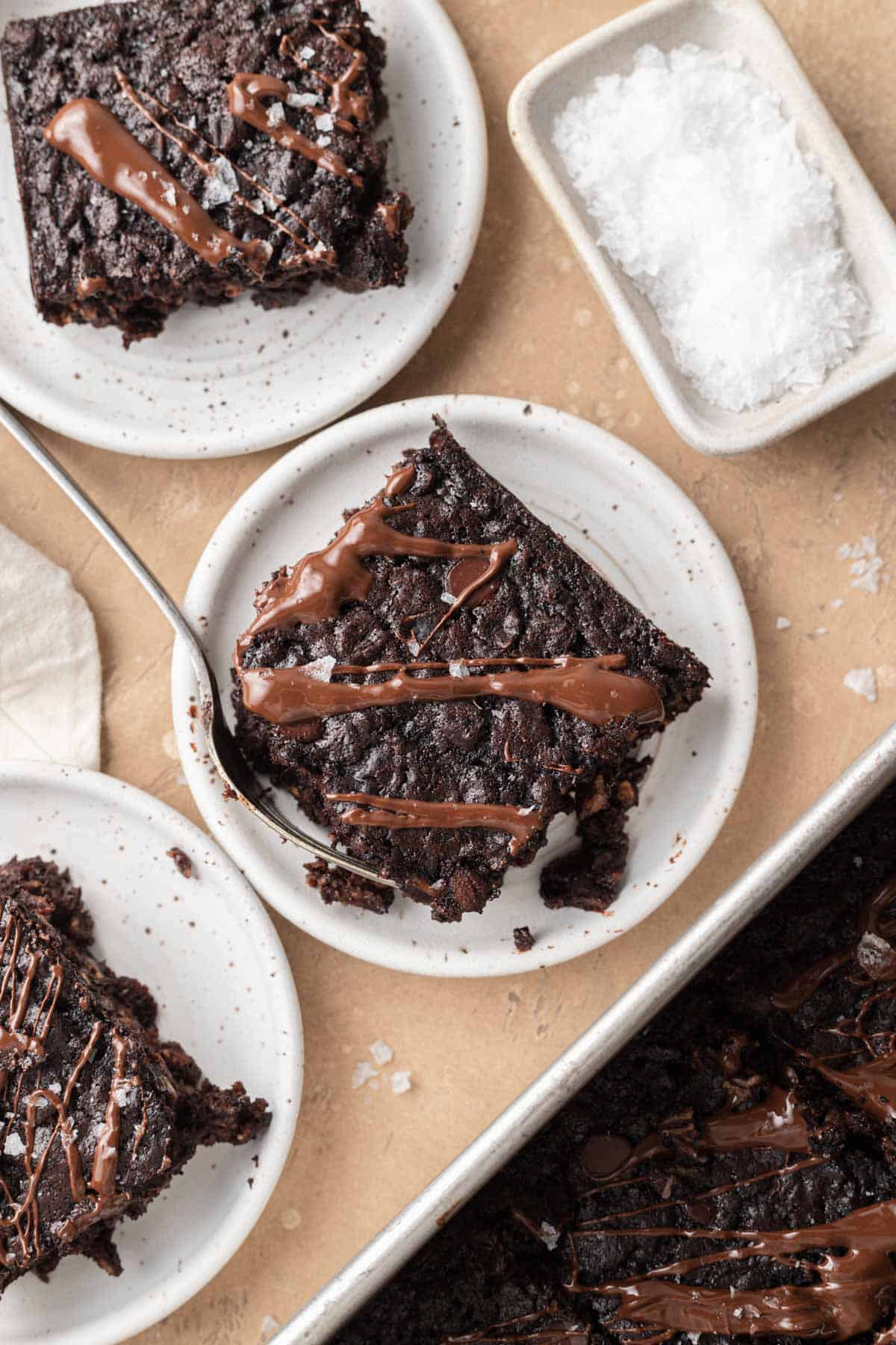 slices of brownie baked oatmeal on plates with a dish of flakey sea salt.