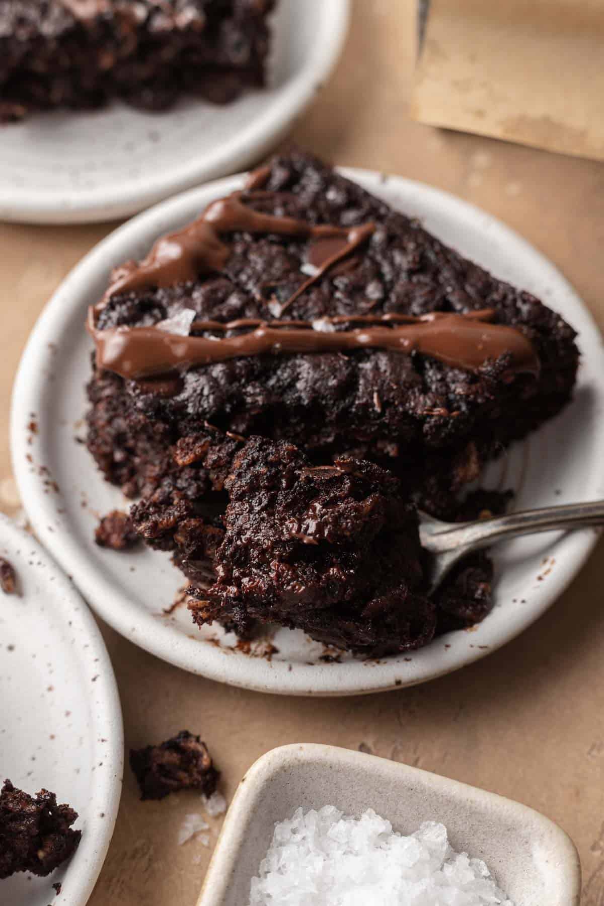 bite of brownie baked oats being taken from a slice on a plate with a fork.