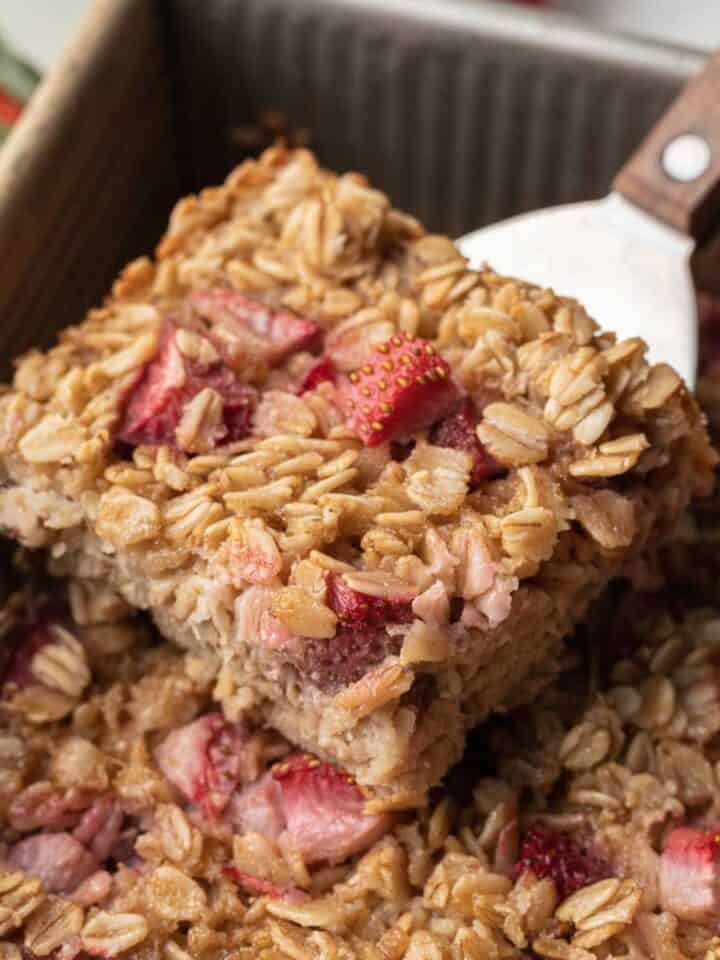 a piece of strawberry baked oats being taken from pan