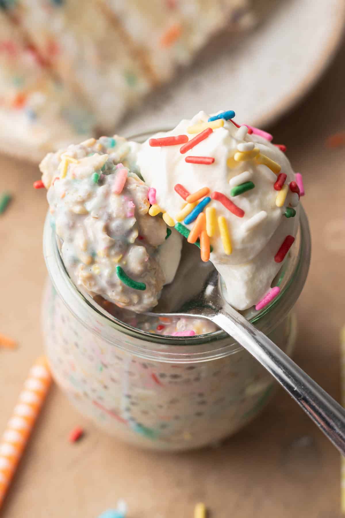 spoon taking a scoop out of the top of birthday cake overnight oats.