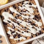 overhead view of blueberry lemon baked oats in a white dish, with lemon yogurt icing drizzled on top.