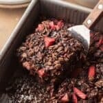a slice of chocolate strawberry baked oatmeal being scooped out of baking dish.