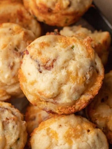 Close-up of savory cheese and bacon muffins stacked together on a tray.