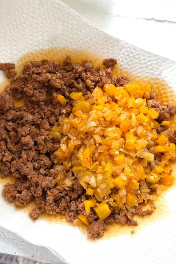 Cooked ground chorizo and sautéed yellow bell peppers with onions on a paper towel to drain excess oil.