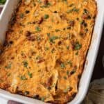 Baked cheesy casserole with tortilla strips, black beans, and herbs in a white dish.
