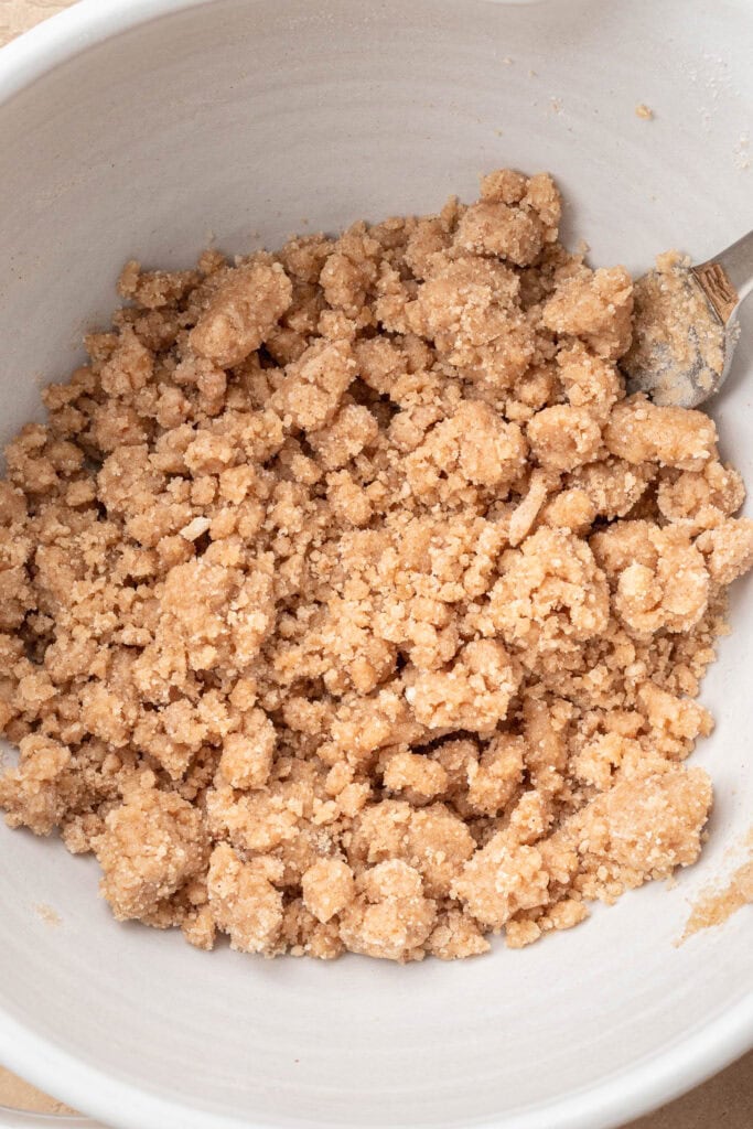 Crumbly brown sugar and butter mixture in a white bowl with a metal spoon.