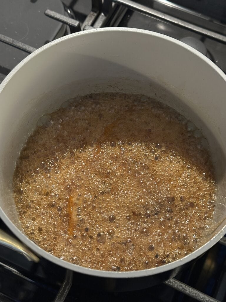 maple syrup bubbling in a pot on a stovetop.