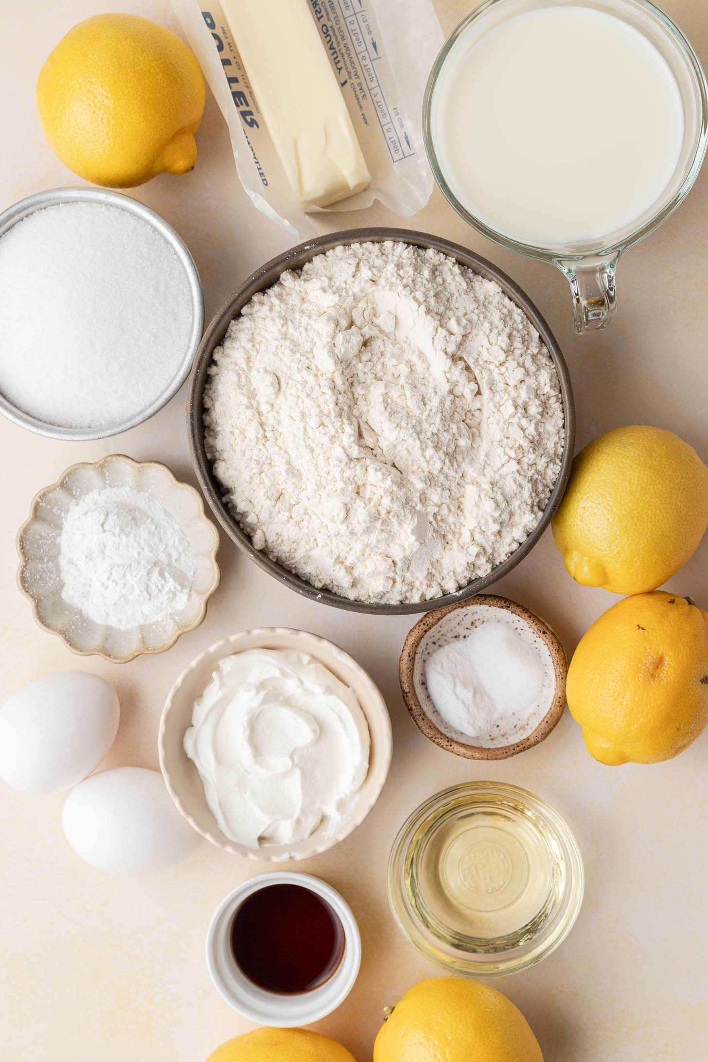 Baking ingredients including flour, sugar, eggs, lemons, butter, milk, sour cream, oil, vanilla, baking powder, and salt.