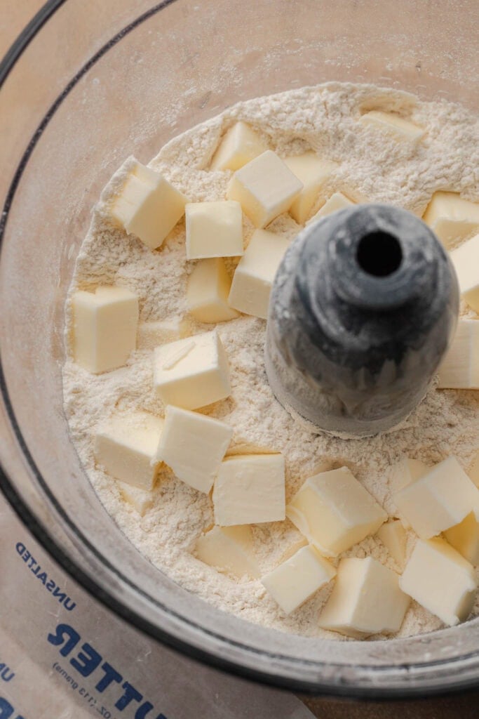 Cubed butter and flour in a food processor bowl, ready to be mixed for baking.