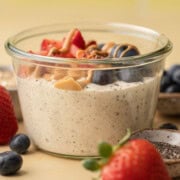 A glass jar of overnight oats topped with strawberries, blueberries, peanut butter, and chia seeds.