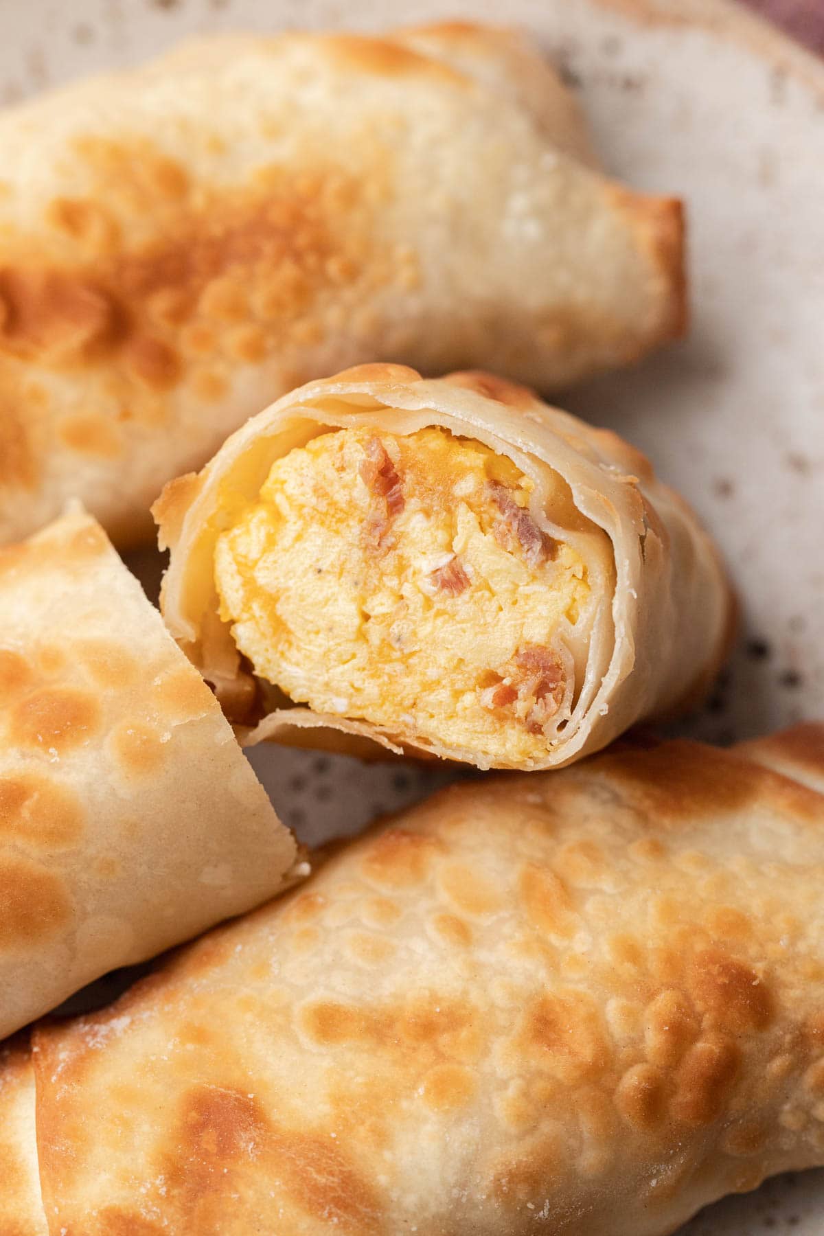 A close-up of a breakfast egg roll cut open, revealing a filling of scrambled eggs and ham.