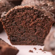 Close-up of a sliced chocolate muffin, showing a moist, rich inside with chocolate chunks.