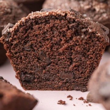Close-up of a sliced chocolate muffin, showing a moist, rich inside with chocolate chunks.