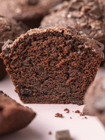 Close-up of a sliced chocolate muffin, showing a moist, rich inside with chocolate chunks.
