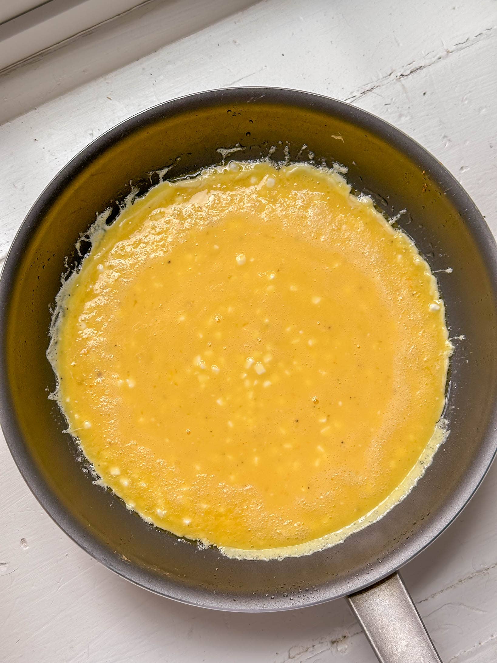 Egg mixture cooking in a nonstick skillet, edges beginning to set.