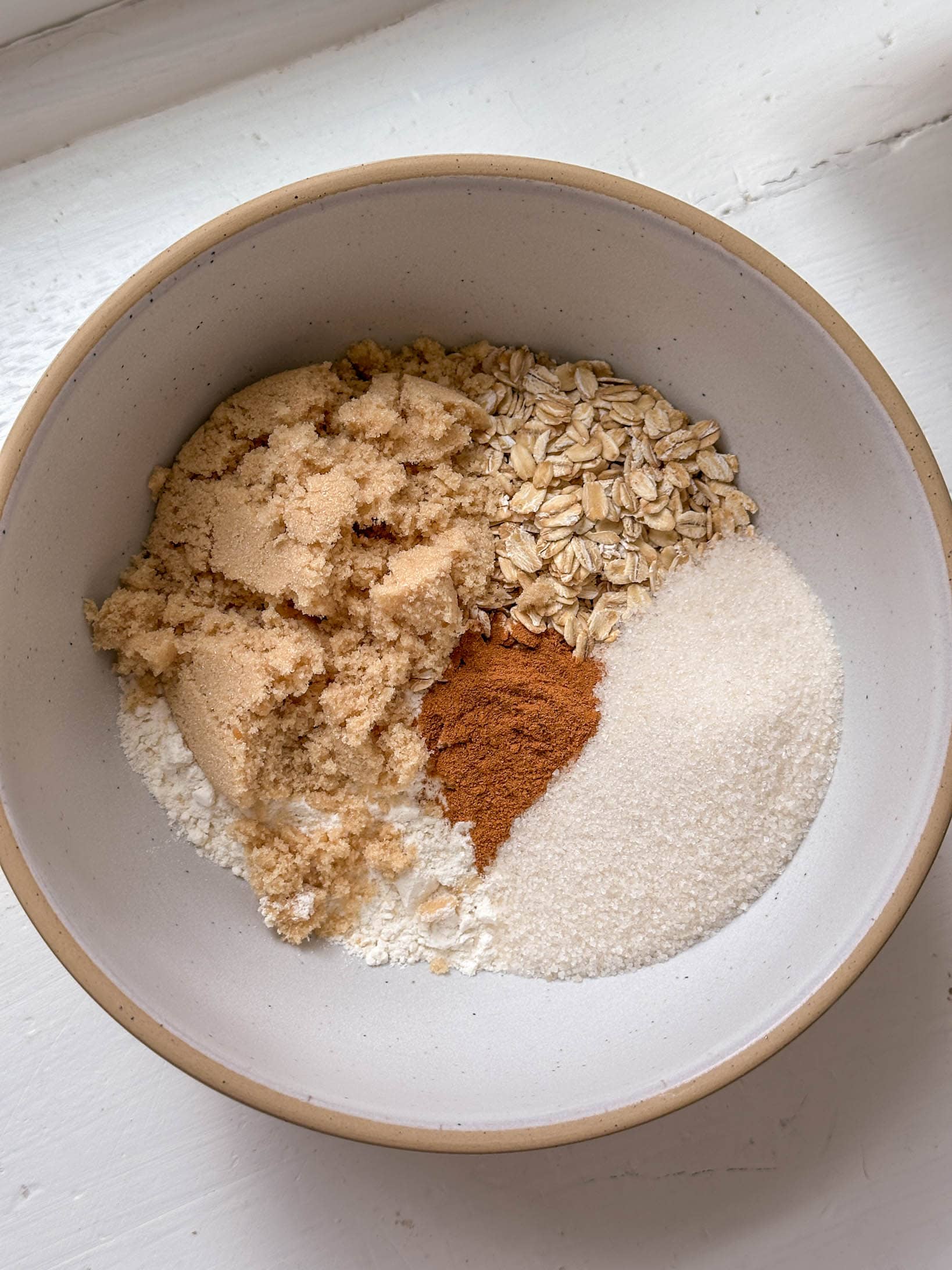 A bowl with oats, brown sugar, white sugar, flour, and cinnamon in separate sections.