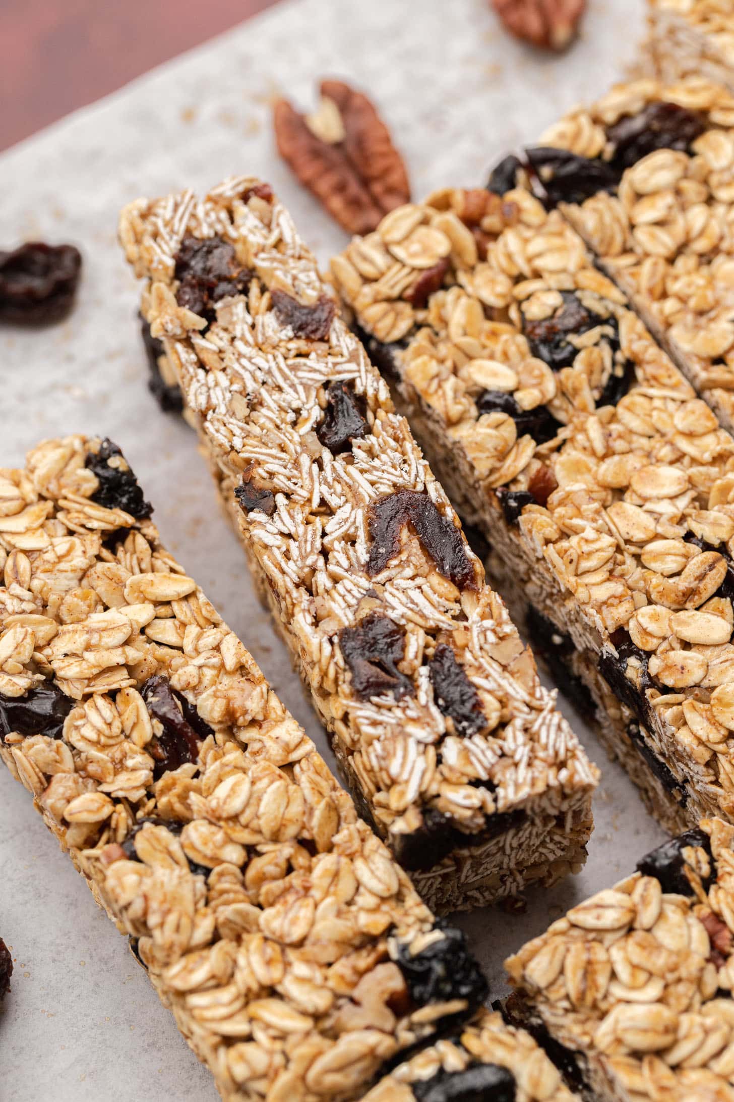 Close-up of oat granola bars with dried fruit and nuts on parchment paper.
